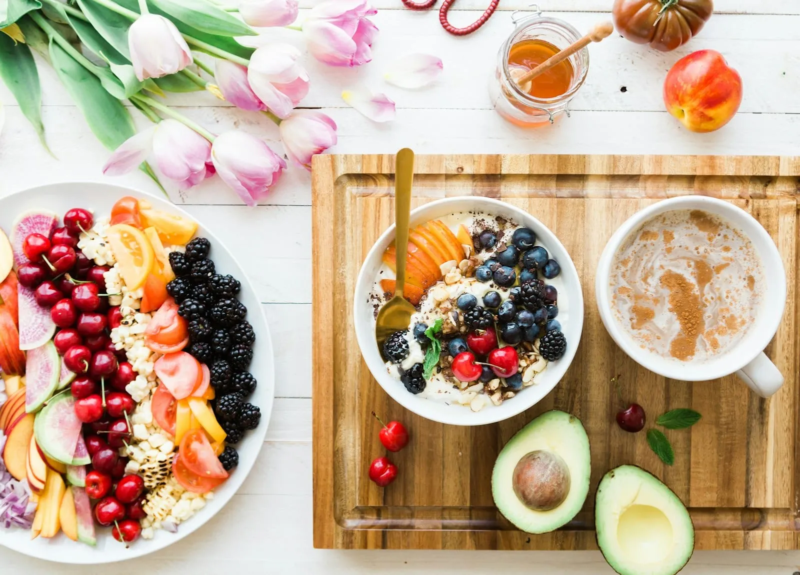 A breakfast table with fruit, oatmeal bowls, avocado and coffee