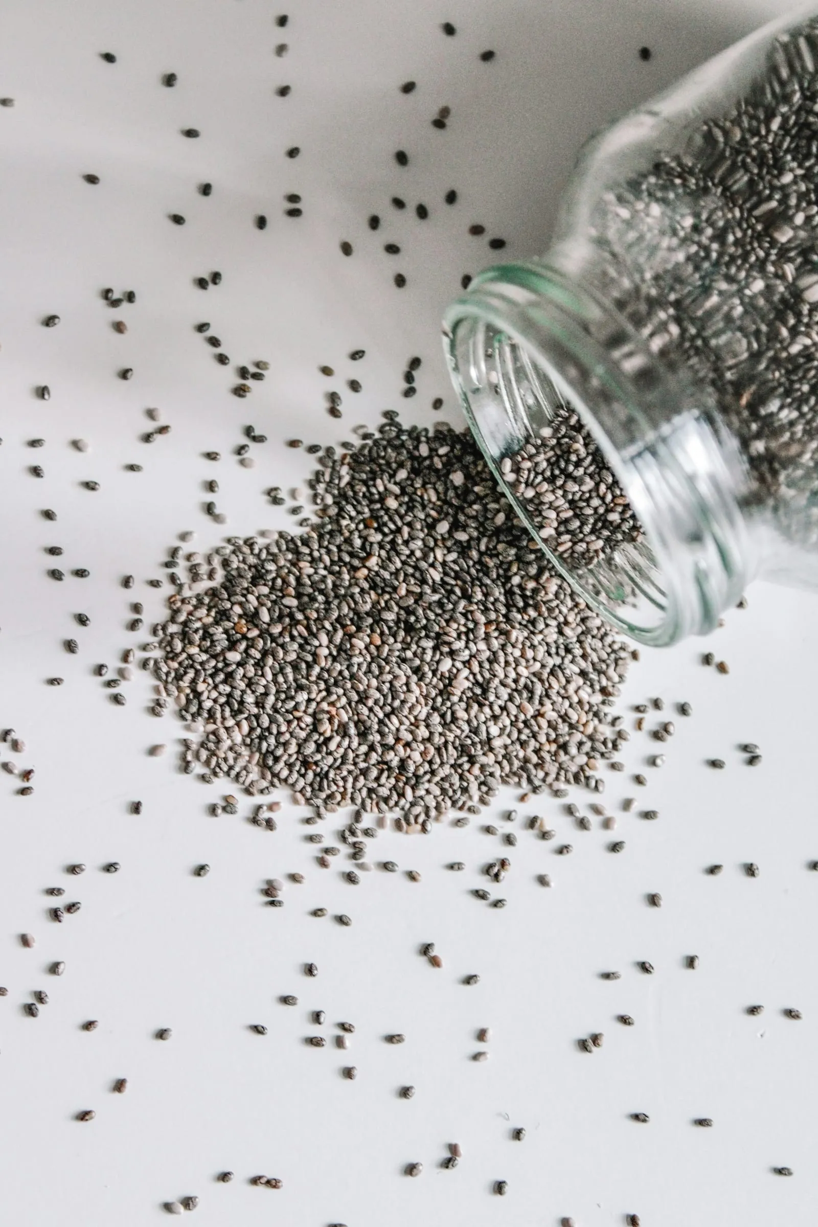 Chia seeds spilling from a glass jar