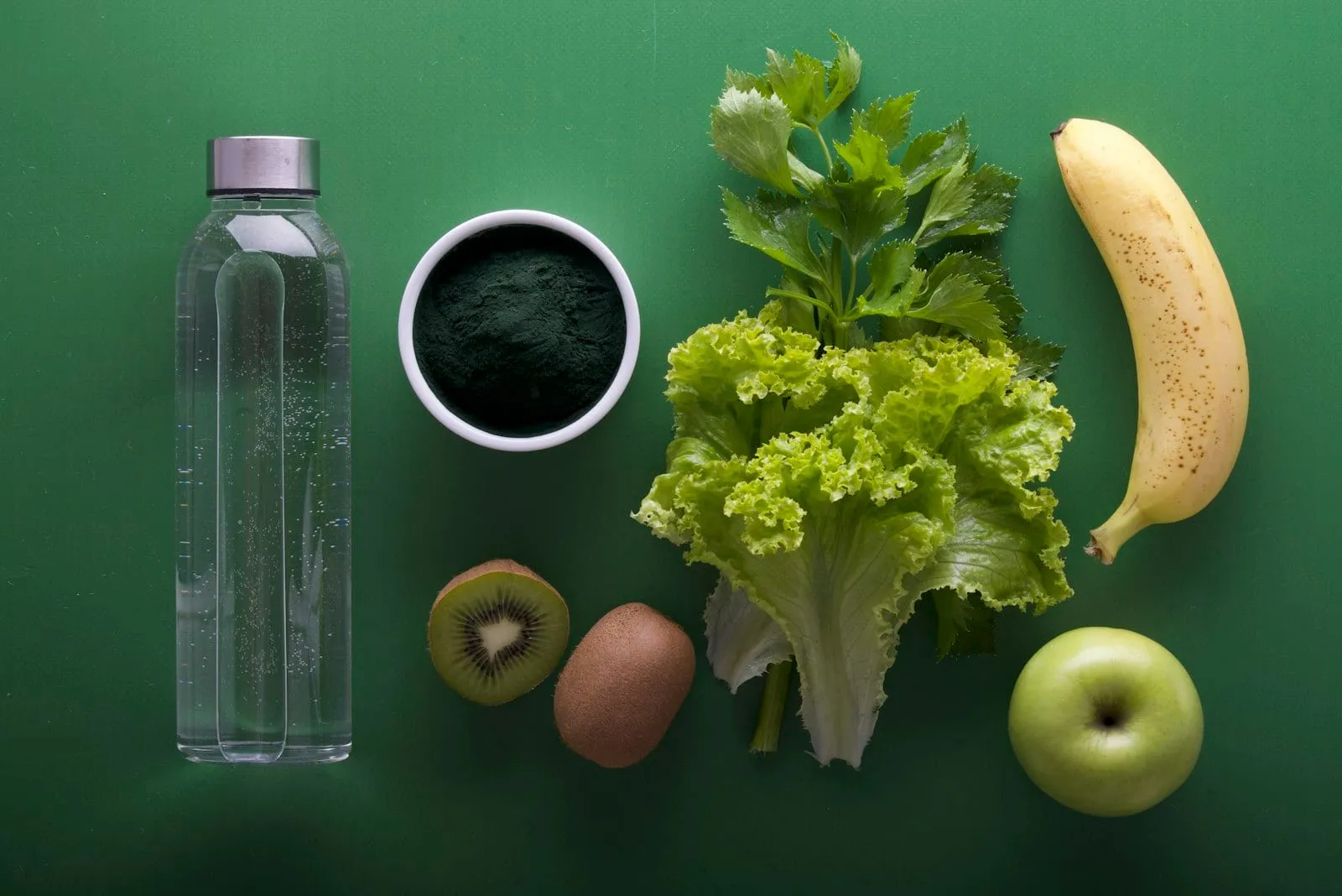 Fiber-rich foods including leafy greens, kiwi, apple and banana on a green background
