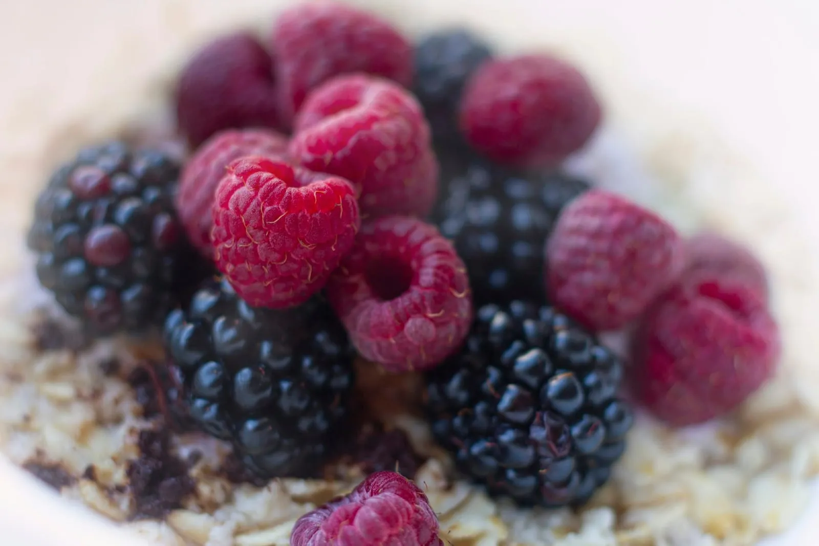 A bowl of oatmeal topped with raspberries and blackberries