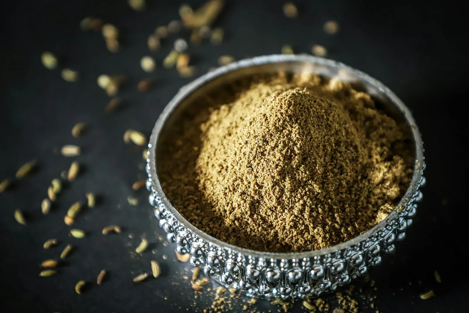 Fine psyllium husk powder in a silver bowl surrounded by seeds