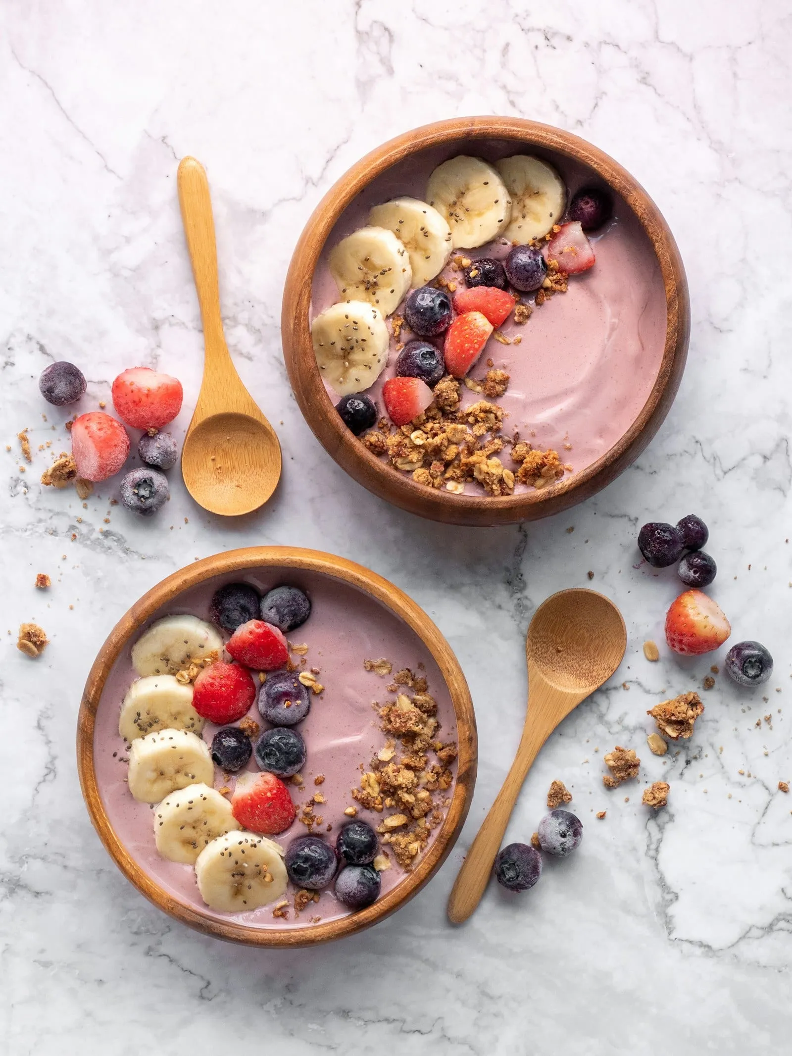 Two smoothie bowls topped with banana, berries and granola